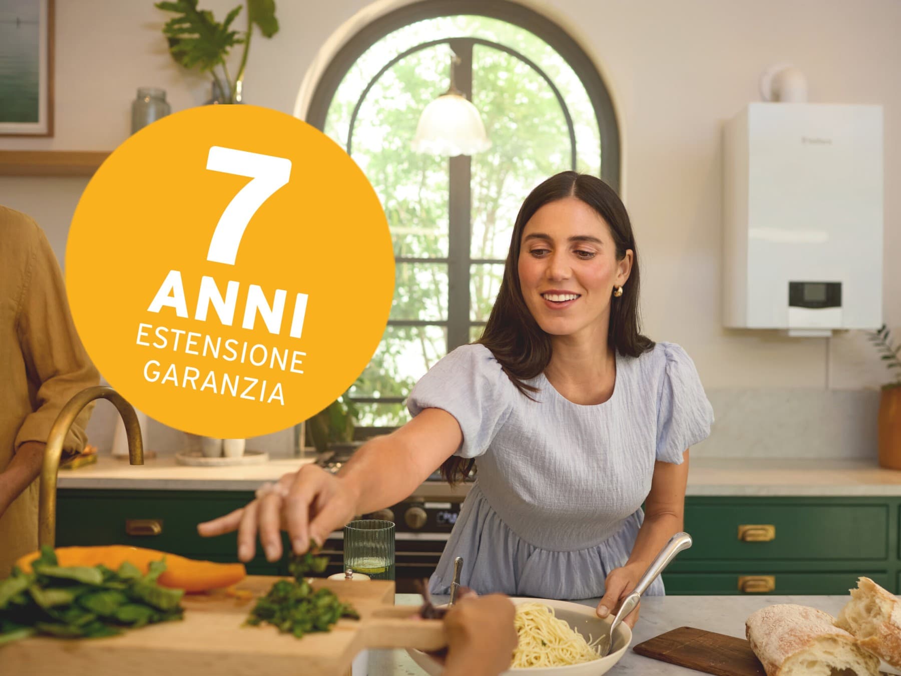Una coppia in cucina che prepara il pranzo. Sullo sfondo, caldaia Vaillant.