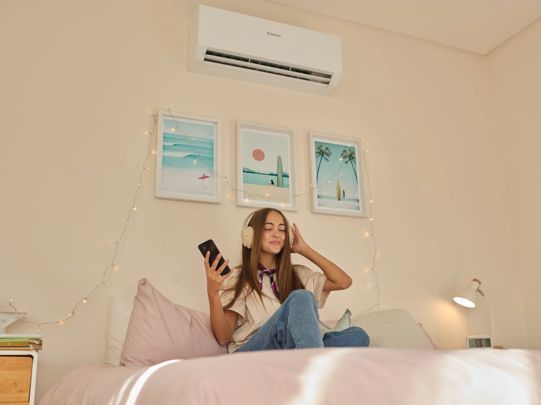 Ragazza ascolta musica in camera da letto. Alle spalle, un climatizzatore Vaillant.
