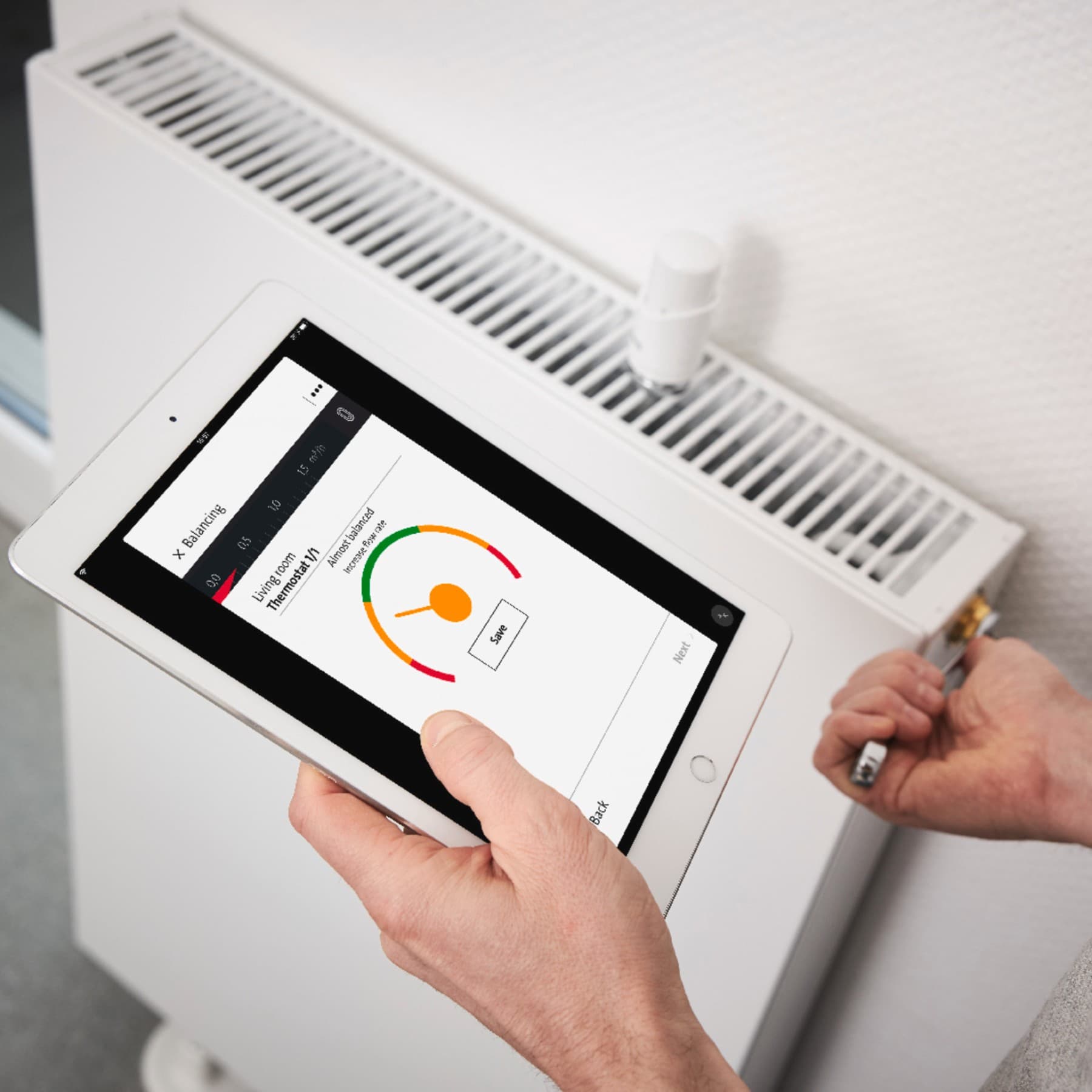 Installatore con un tablet in mano che controlla la temperatura di un termosifone.