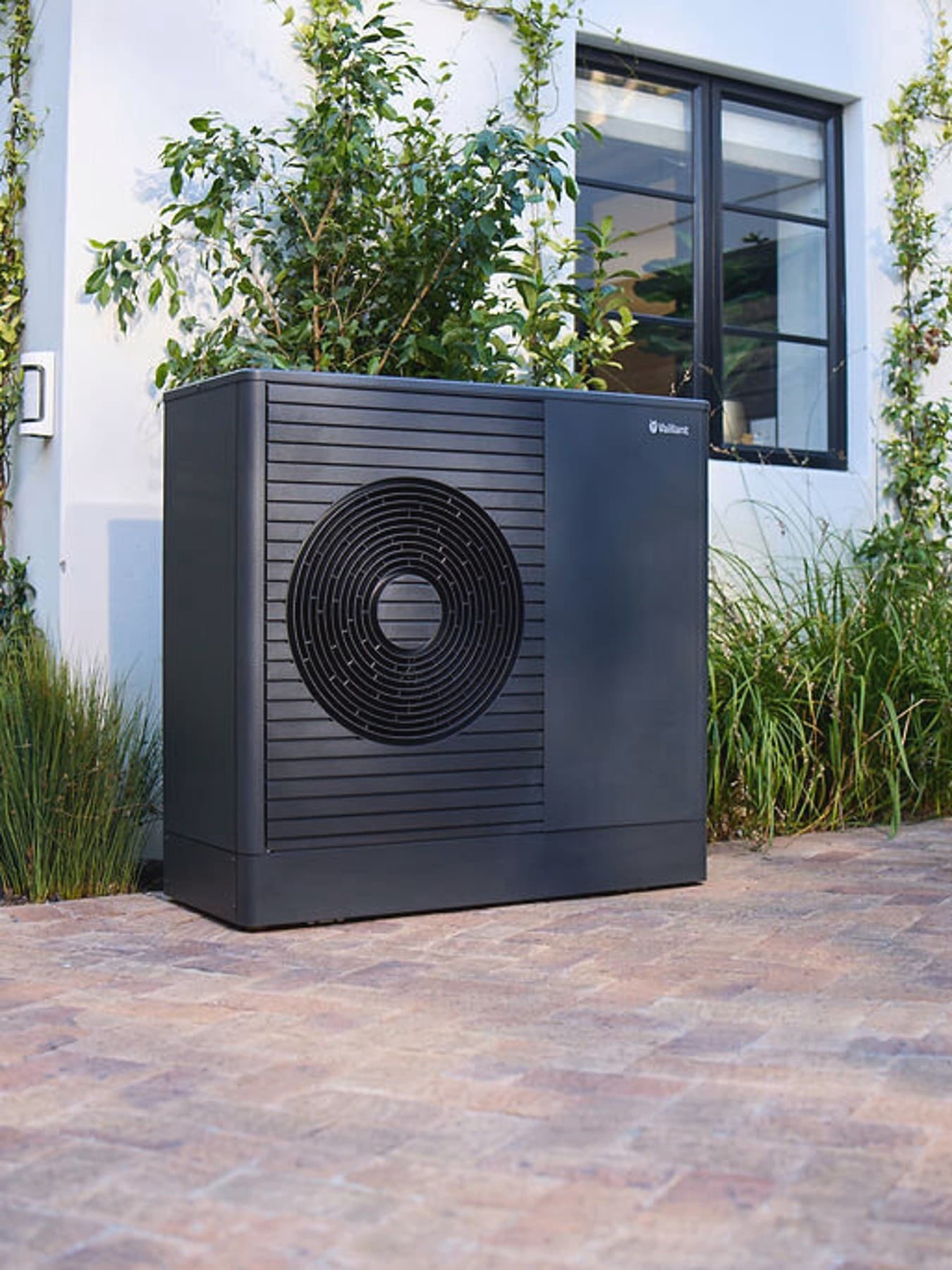 Pompa di calore Dark Vaillant aroTHERM plus nel giardino antistante una casa
