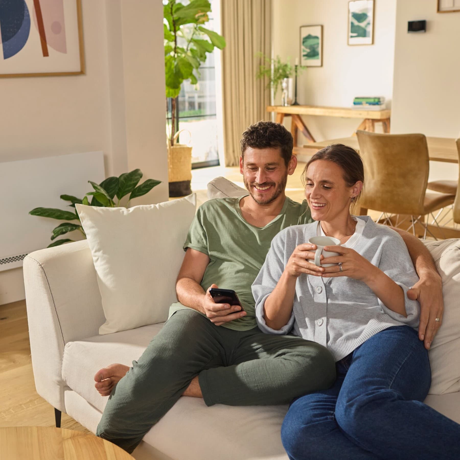 Coppia seduta sul divano che guarda uno smartphone
