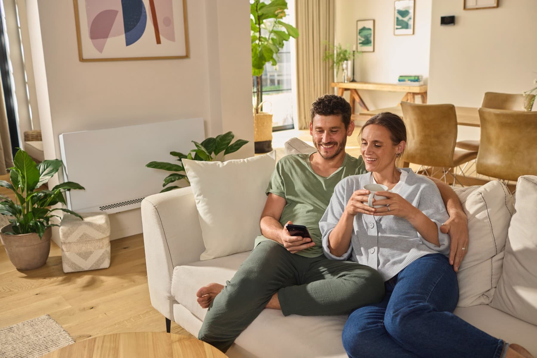 Coppia seduta sul divano che guarda uno smartphone