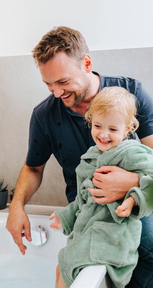 Un padre e un bambino seduti accanto alla vasca da bagno.