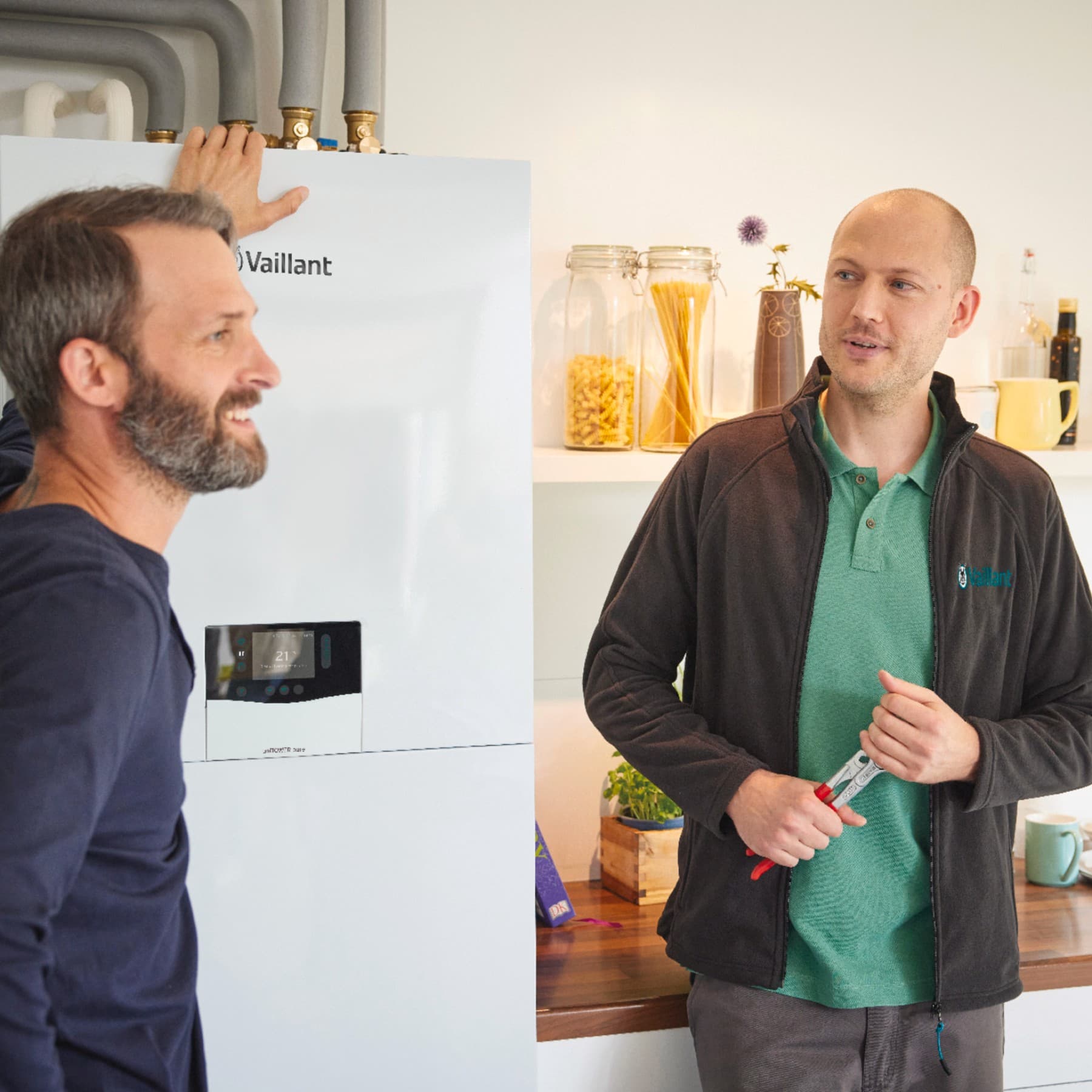 Tecnico e cliente in cucina discutono del funzionamento della pompa di calore per termosifoni