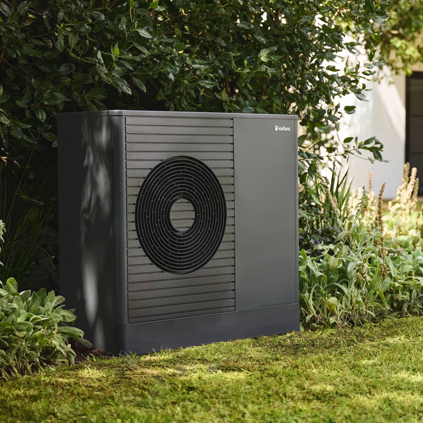 Pompa di calore davanti alla siepe del giardino