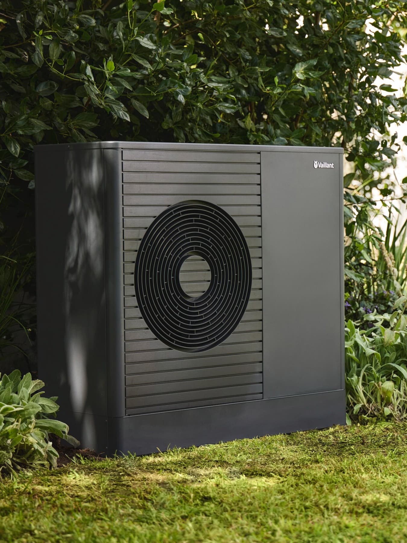 Pompa di calore davanti alla siepe del giardino