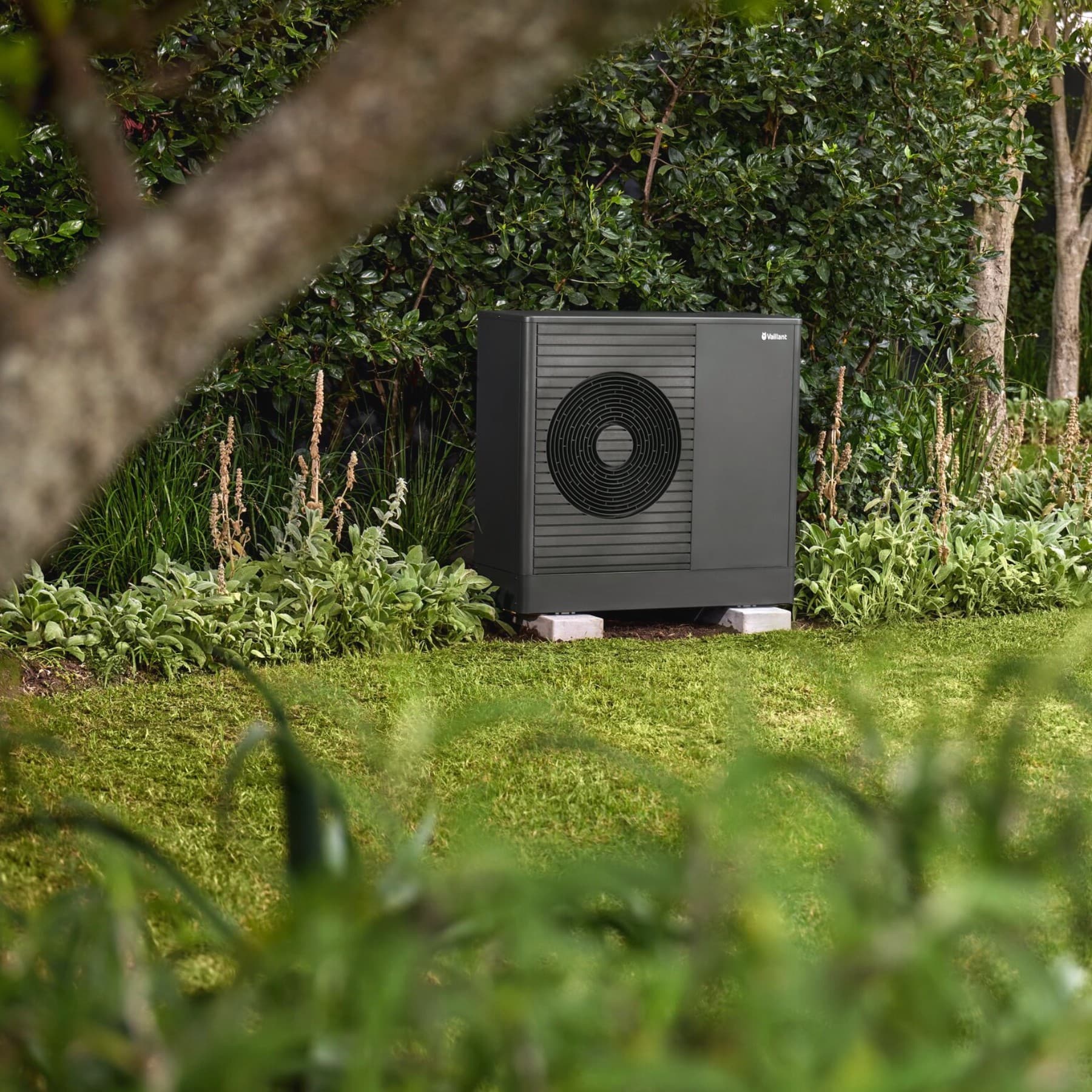 Pompa di calore Vaillant nel giardino davanti a una casa.