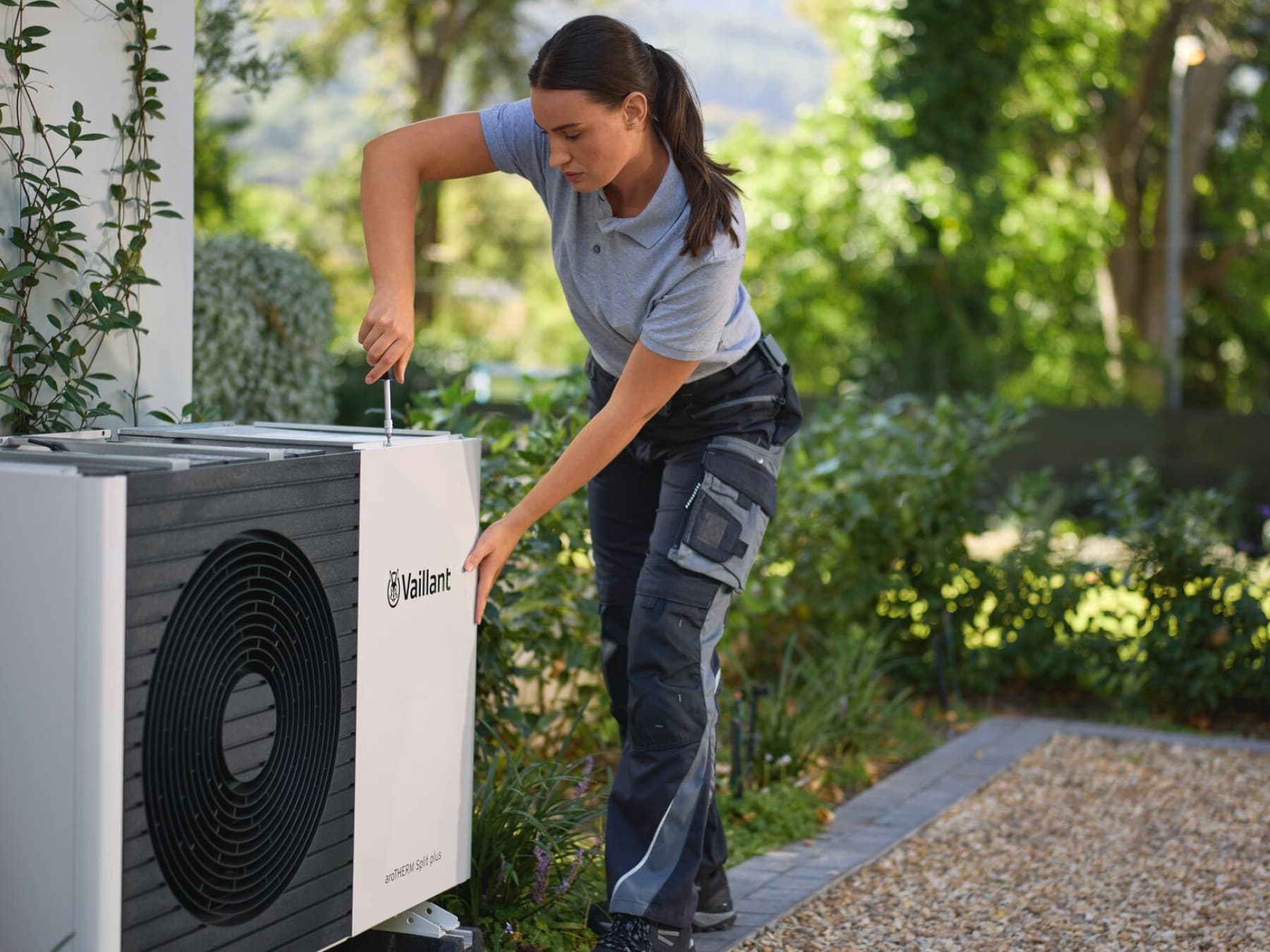 Bambino seduto sopra a una pompa di calore Vaillant.