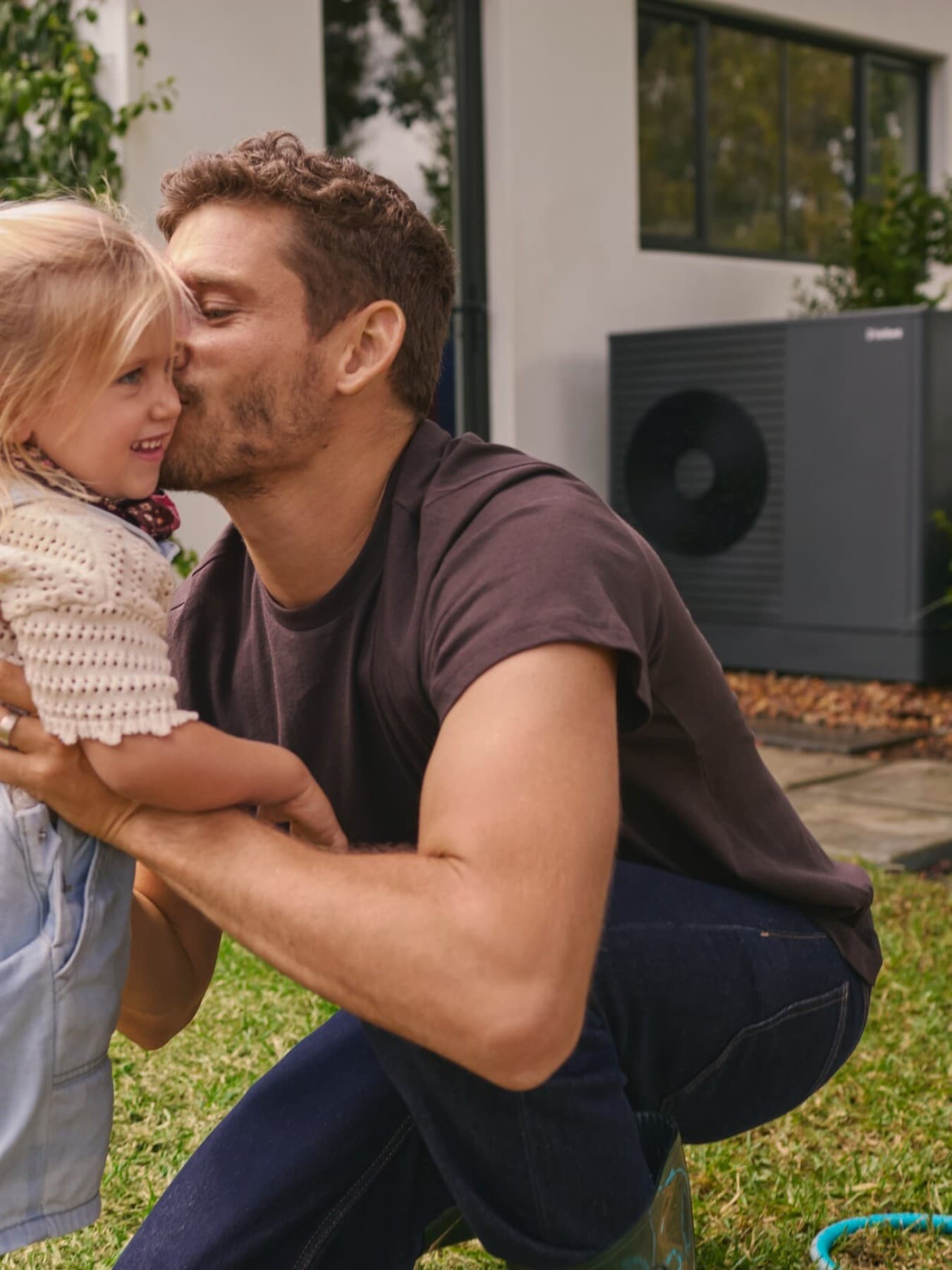 Padre con figlia in giardino davanti a pompa di calore Vaillant aroTHERM plus.