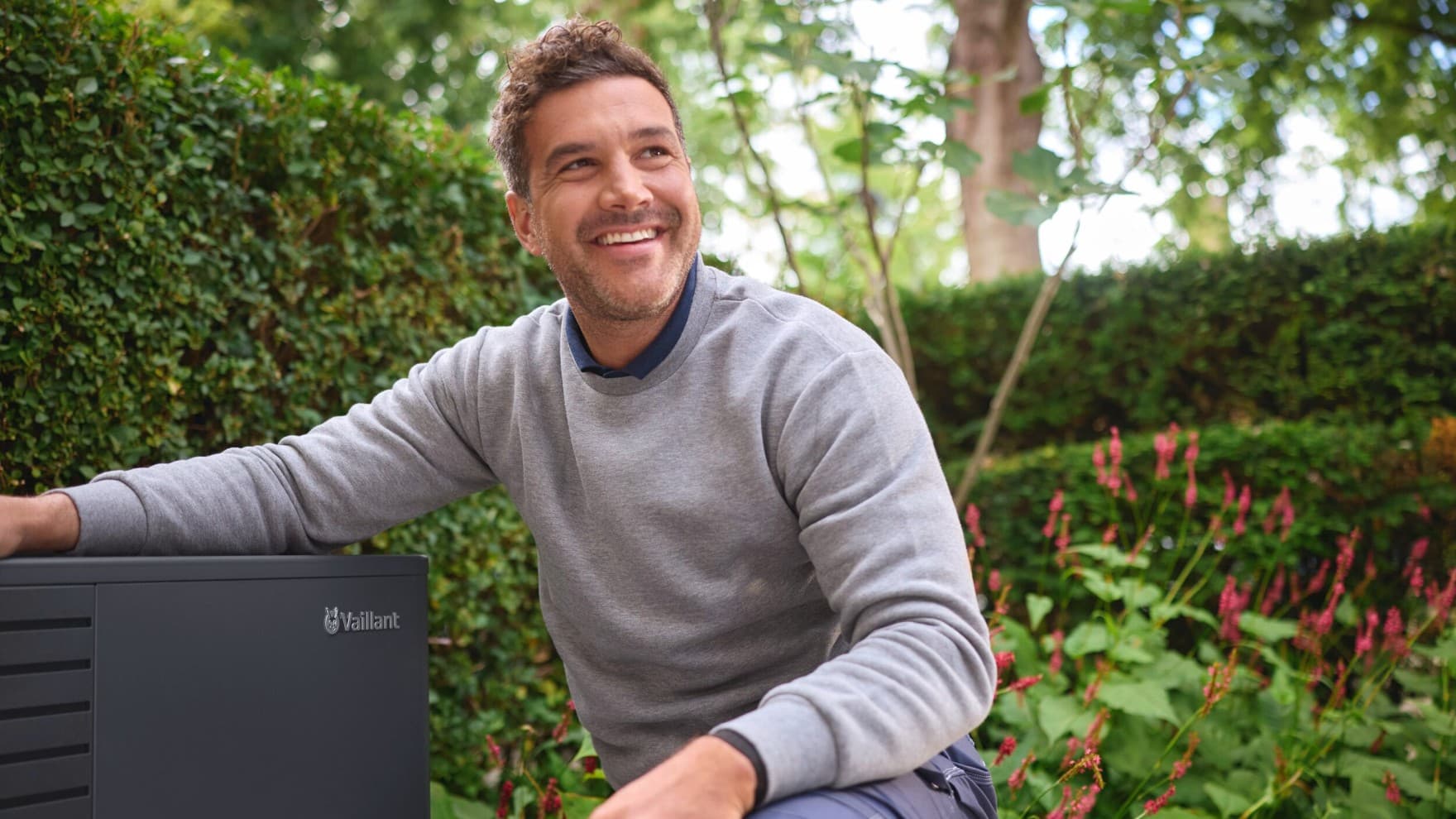 Uomo in giardino con una pompa di calore Vaillant.