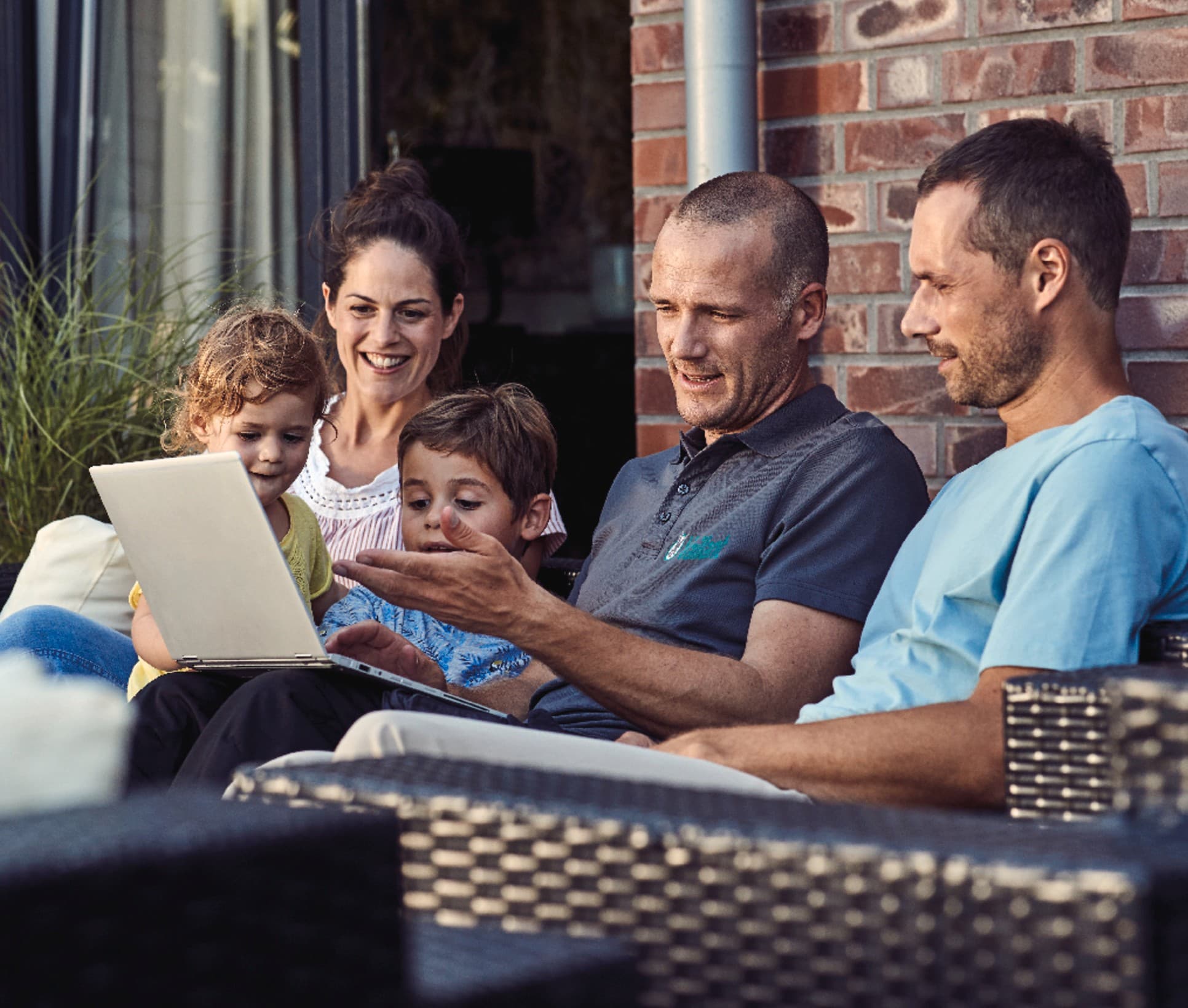 Tecnico Vaillant che mostra informazioni su laptop a una famiglia con bambini in terrazzo