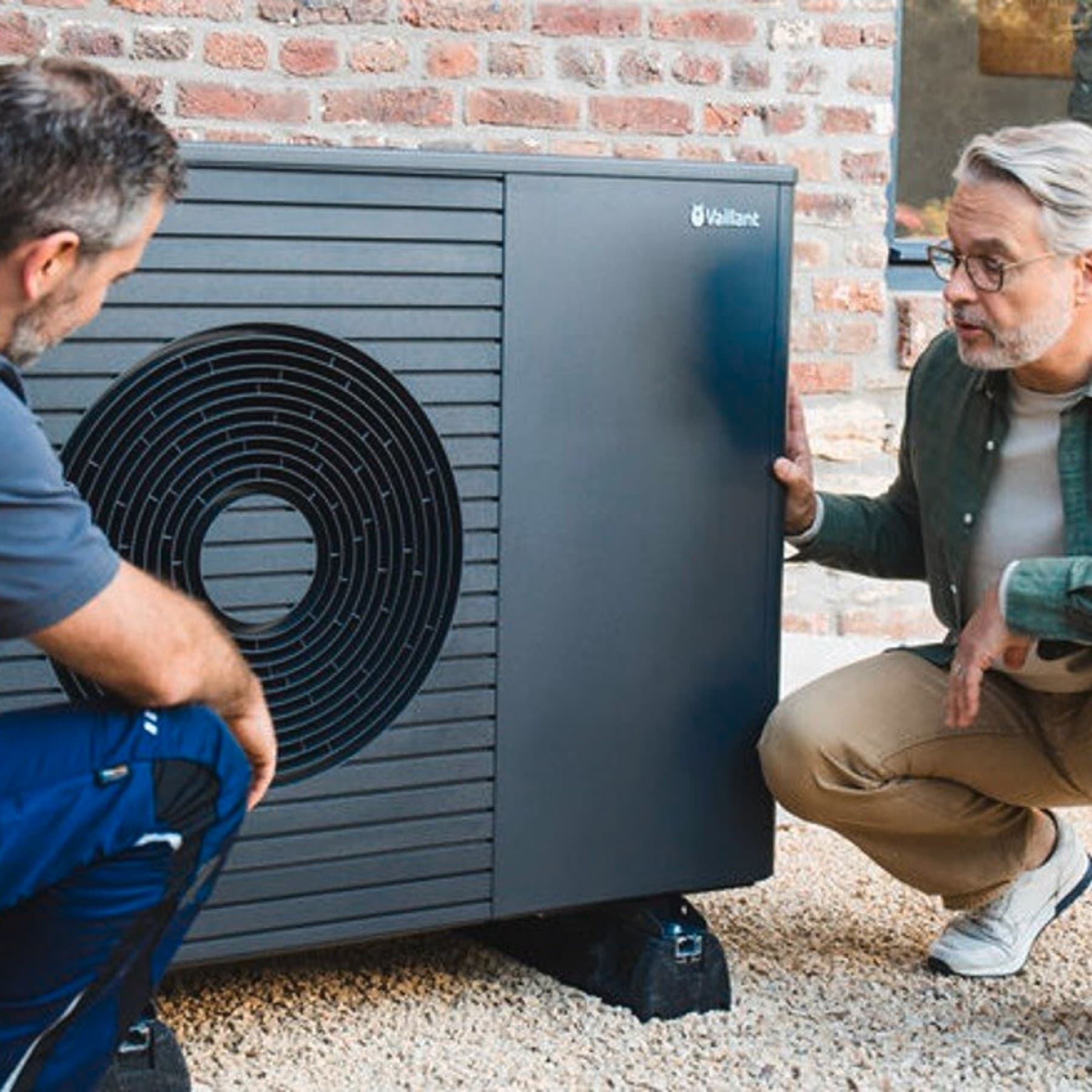 Un uomo di mezza età che osserva come un installatore installa una pompa di calore