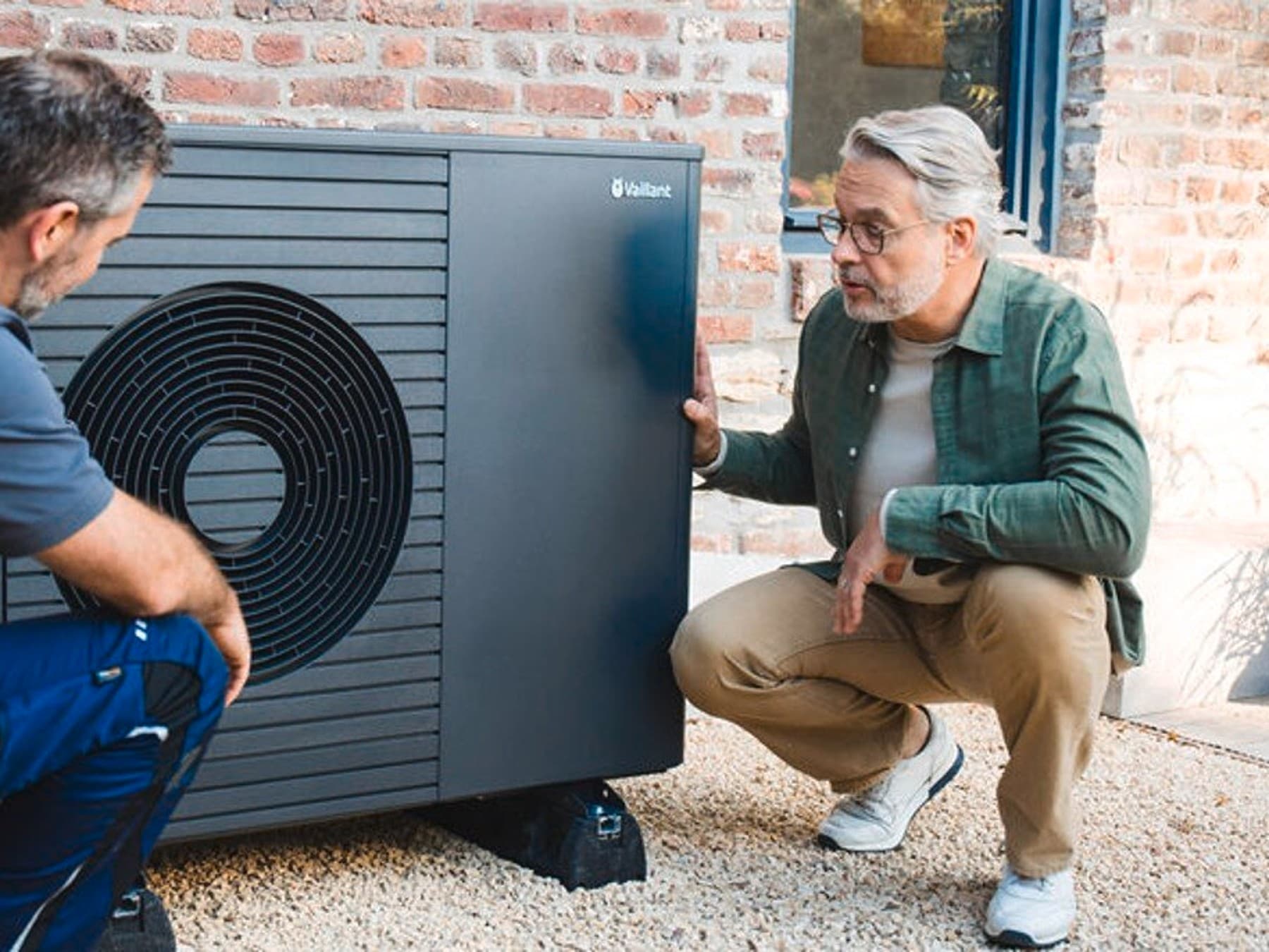 Tecnico dell'assistenza che lavora su una pompa di calore davanti a un uomo