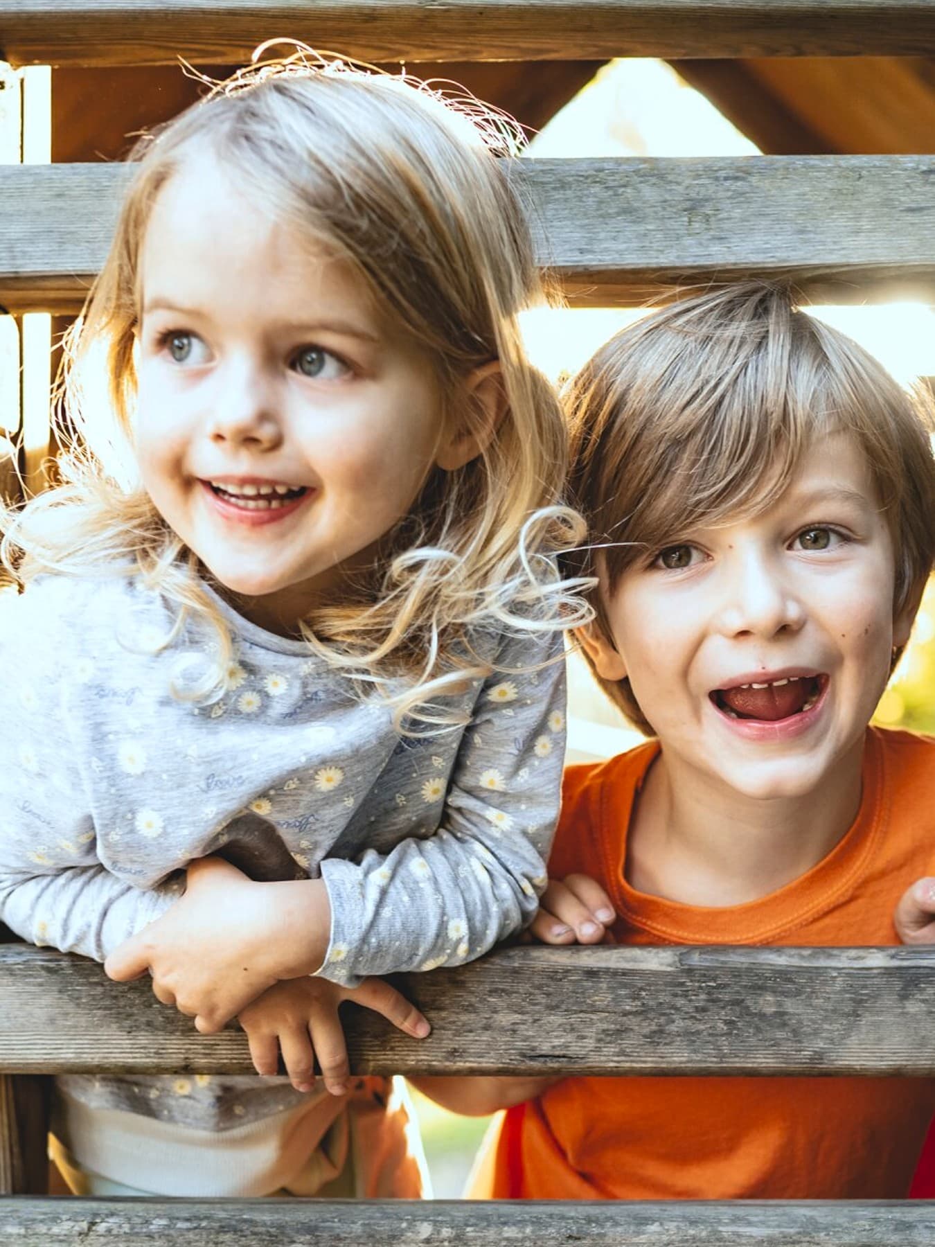 Due bambini che giocano in una capanna di legno in un parco giochi