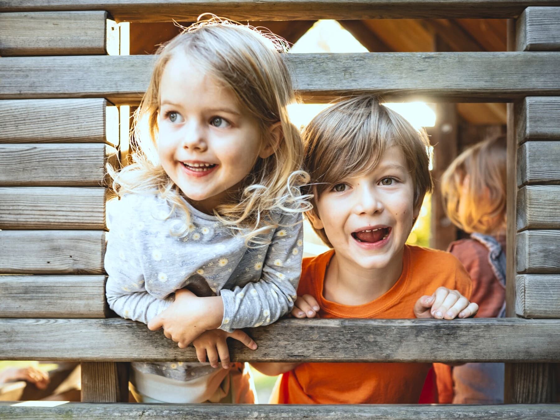 Due bambini che giocano in una capanna di legno in un parco giochi