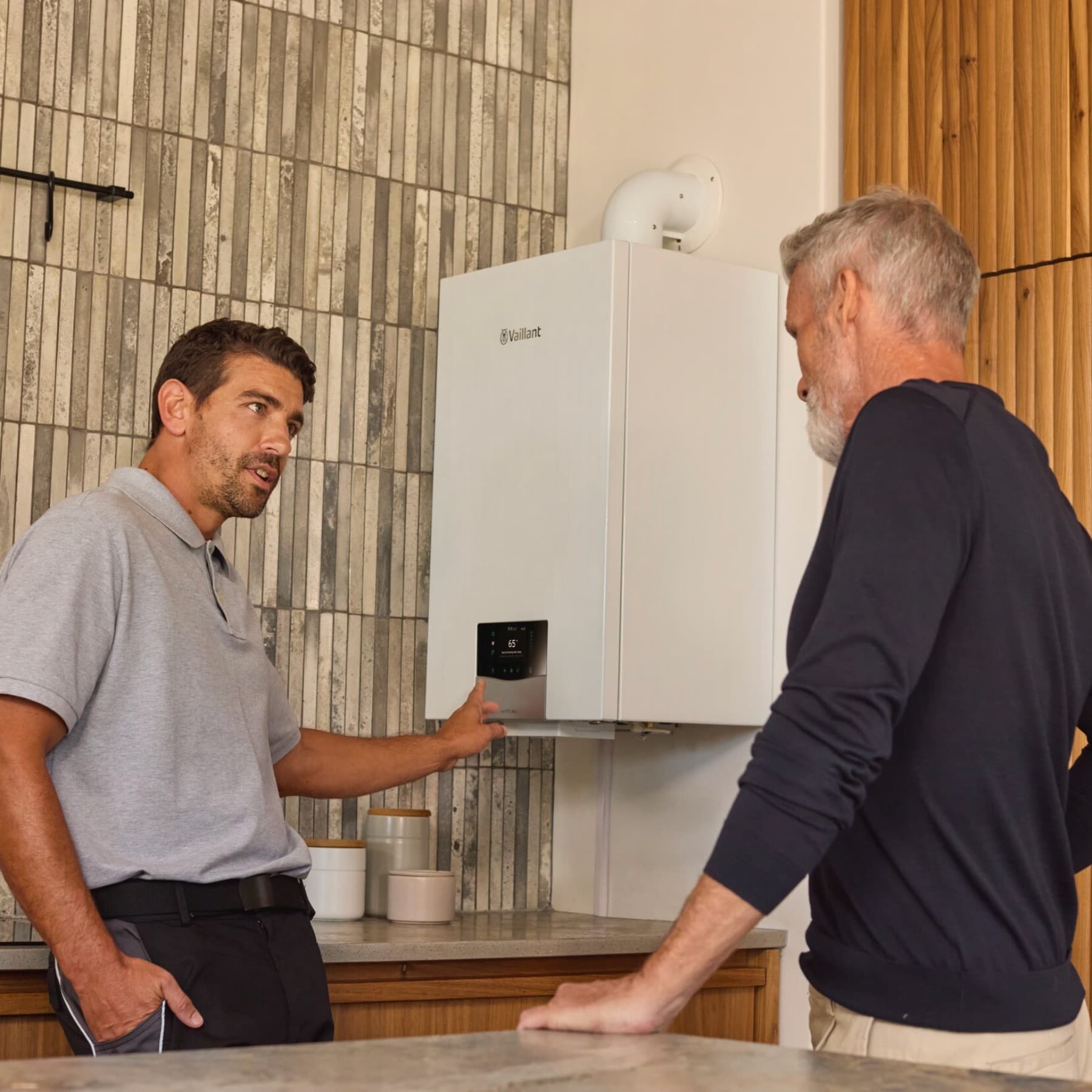 Installatore che indica la caldaia e fornisce spiegazioni a un cliente